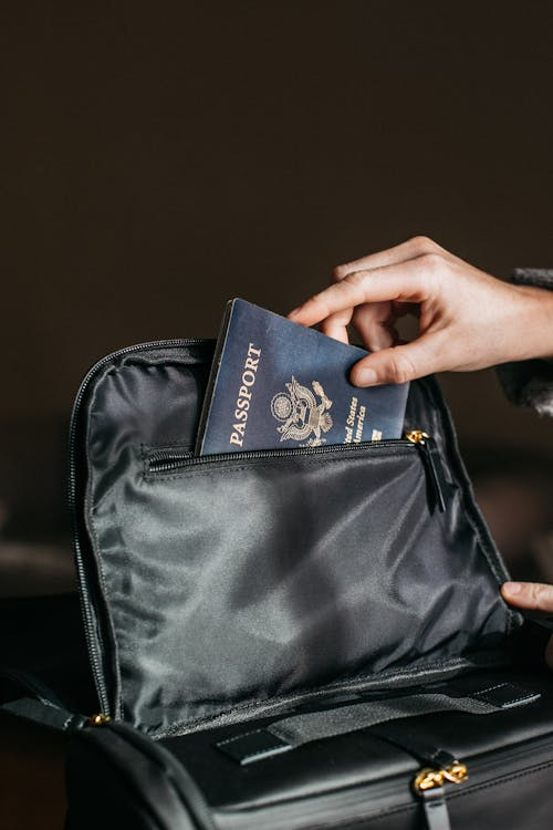 An individual placing their passport in a bag